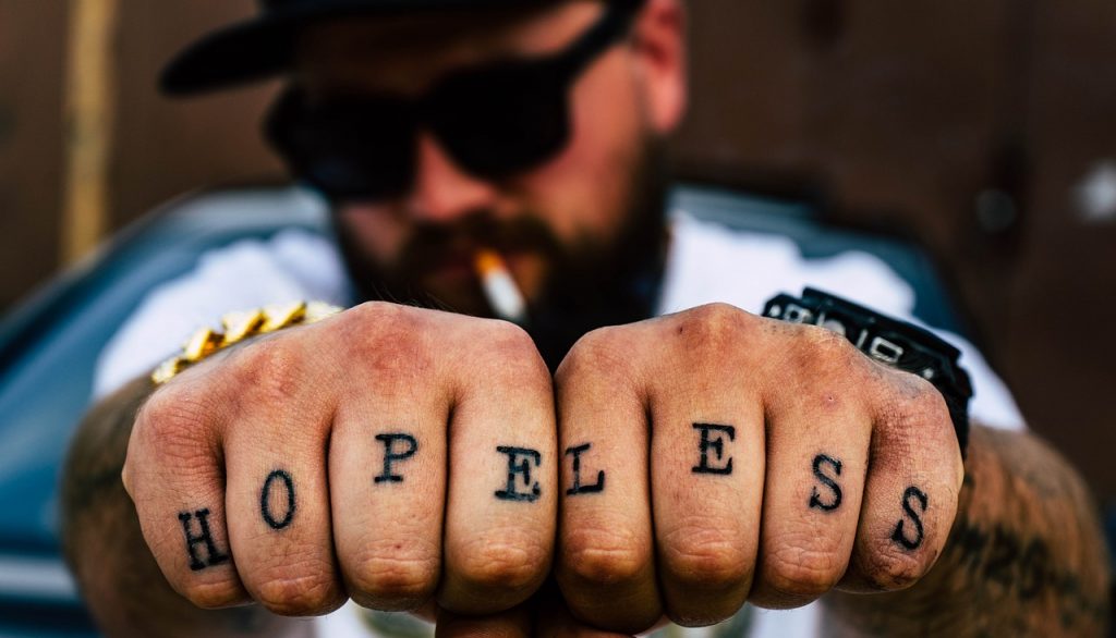 Tatuaż w formie napisu wykonany na palcach u dłoni mężczyzny