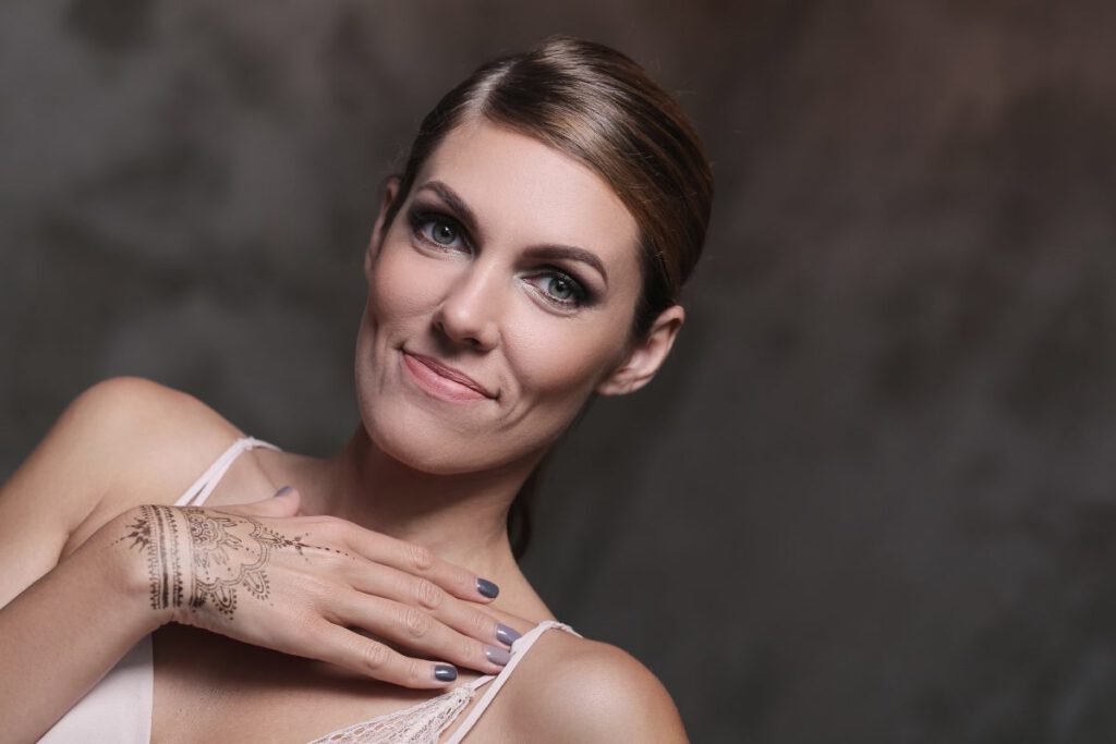 Uśmiechnięta młoda kobieta mająca na dłoni tatuaż