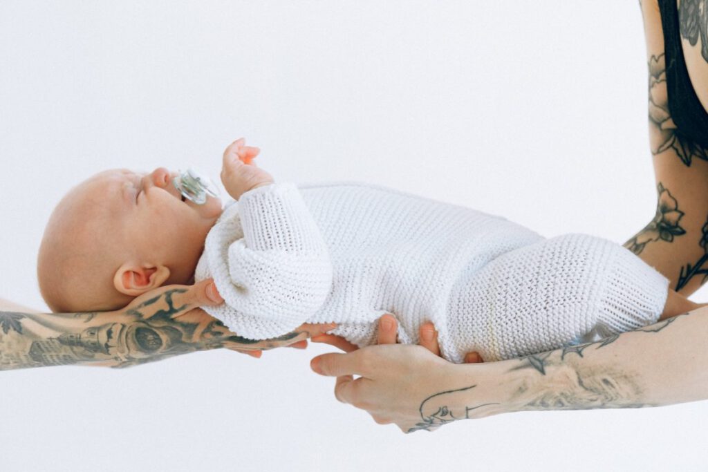 Rodzice mający tatuaże na dłoniach trzymają swoje nowonarodzone dziecko