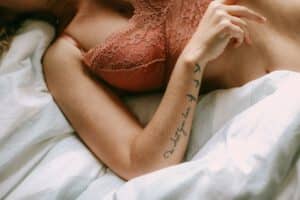 Tatuaż damski napis na ręce kobiety leżącej w łóżku