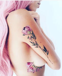 Kobieta o różowych włosach z damskim tatuażem na ciele