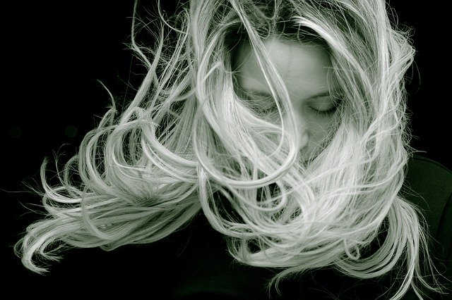 kobieta z długimi włosami której wiatr rozwiewa włosy
