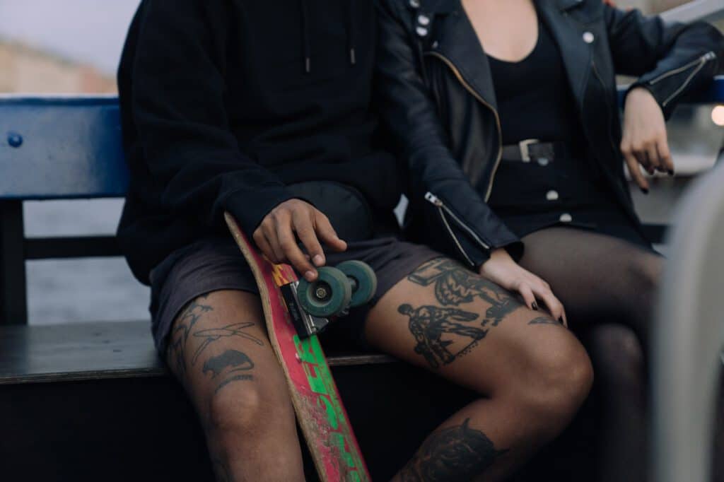 Tatuaże u mężczyzny trzymającego deskorolkę