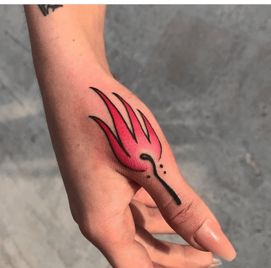 Malutki kolorowy tatuaż wykonany na ręce, we wzorze małej płonącej zapałki