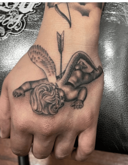 Tatuaż na dłoni prezentujący anioła przebitego strzałą