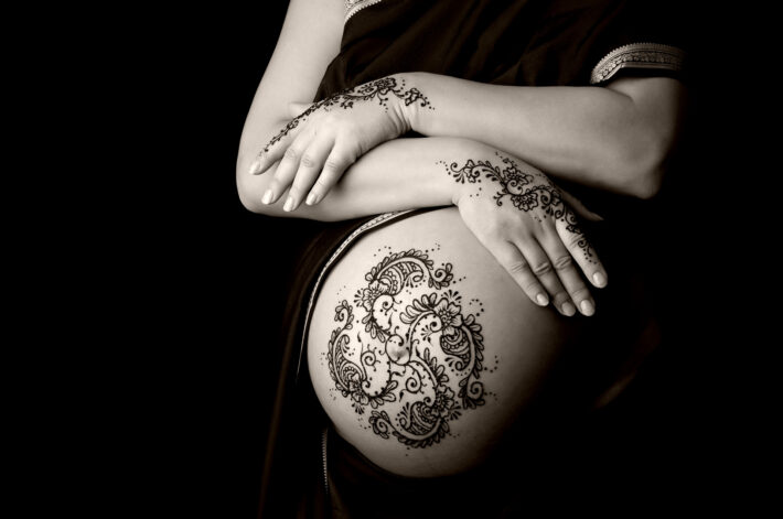 Kobieta w zaawansowanej ciąży z wytatuowanym brzuszkiem