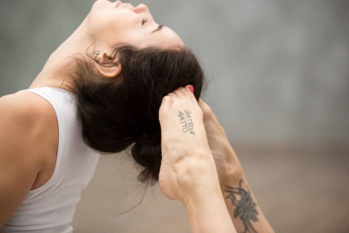 Młoda kobieta ćwicząca jogę z tatuażami na stopie