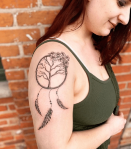 Łapacz snów tattoo u młodej kobiety na ramieniu