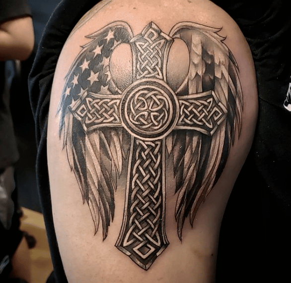 Krzyż celtycki na ręce mężczyzny otoczony skrzydłami anioła