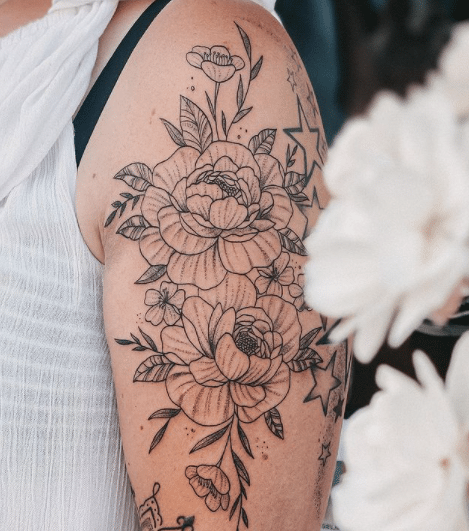 Kobieta ma zrobiony niezwykle kobiecy tatuaż kwiatowy idealnie pasujący do jej ramienia