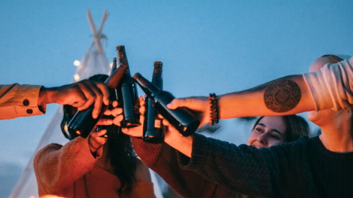 Zdjęcie grupy osób, z których jedna ma tatuaż i również pije alkohol