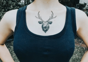 Kobieta w podkoszulku z widocznym tatuażem jeleniem na dekolcie