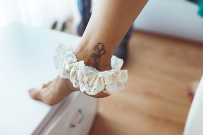 Na kostce osoby ubranej w białą koronkową ozdobę widoczny jest delikatny tatuaż przedstawiający trzy balony