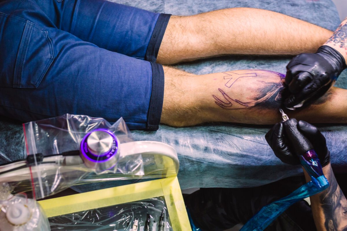 Mężczyzna w studio tatuażu robiący tatuaz na łydce