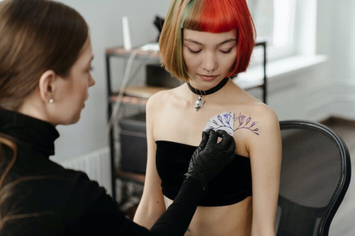 Młoda kobieta tatuuje sobie tatuaż przedstawiający kwiaty blisko kości
