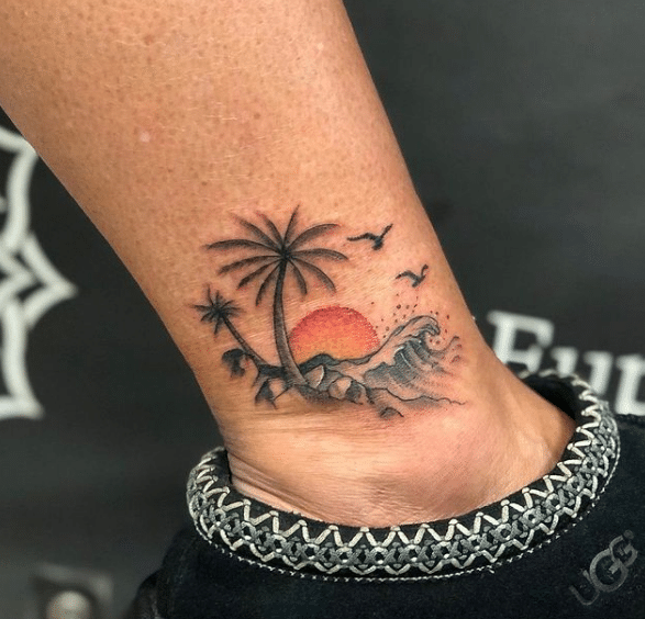 Tatuaż kolorowe palmy i zachód słońca na kostce