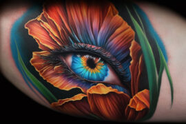 Zmysłowy tatuaż przedstawia oko otoczone płatkami kwiatu w żywych barwach pomarańczu i niebieskiego. Detale i kolorystyka tatuażu są wyjątkowo realistyczne, nadając mu głębię i dynamikę