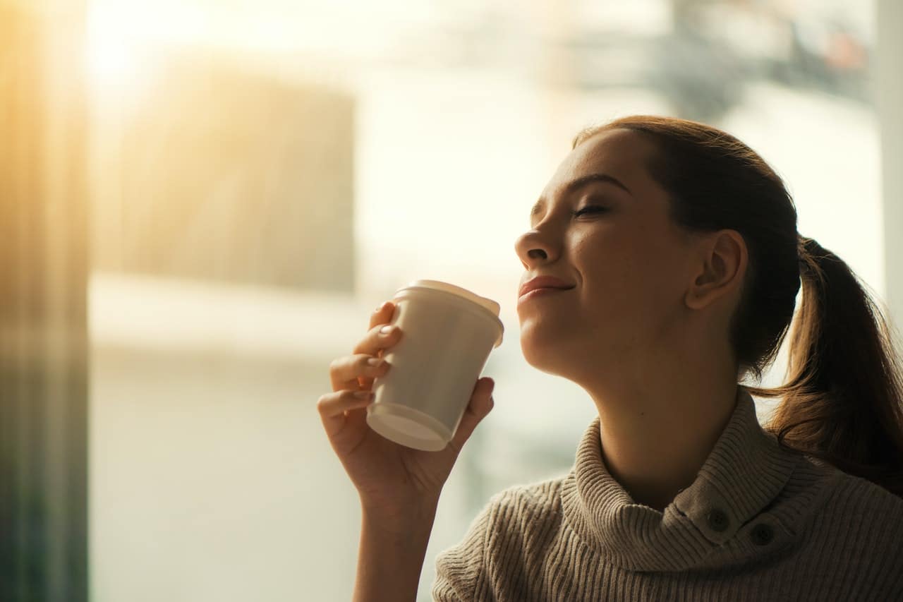 Kobieta pije kawe z jednorazowego kubka