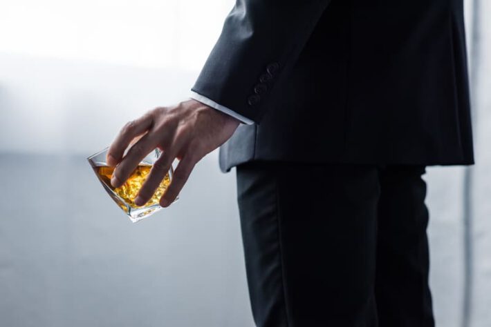 Mężczyzna trzyma w dłoni szklanke z alkoholem