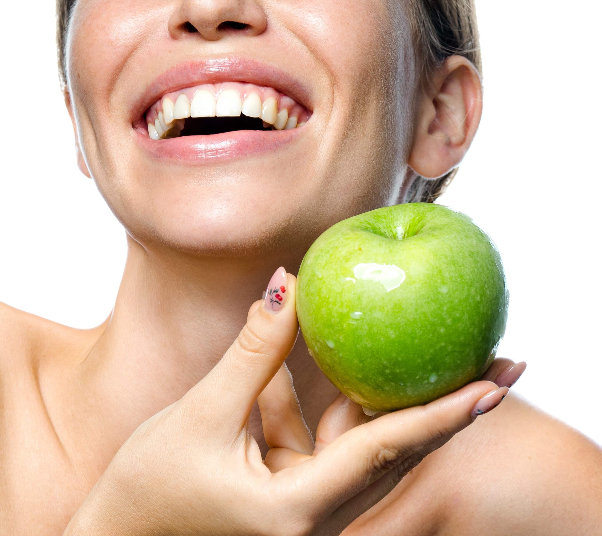 Kobieta uzywajaca wegańskich kosmetyków trzyma jabłko w dłoni