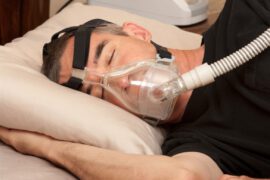 Mężczyzna ma na twarzy aparet CPAP do leczenie bezdechu sennego