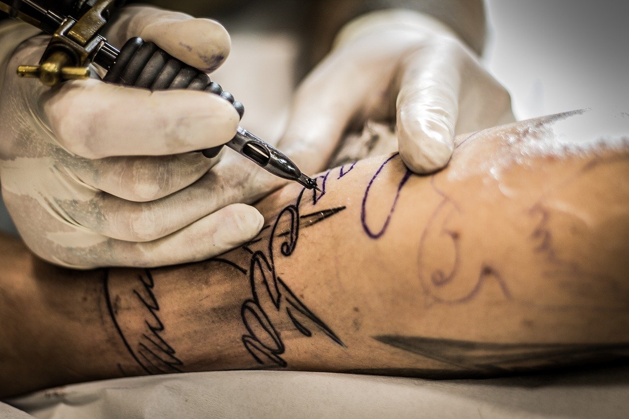 Tatuażysta wykonujący tatuaż na ręce