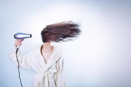 Kobieta susząca włosy suszarką
