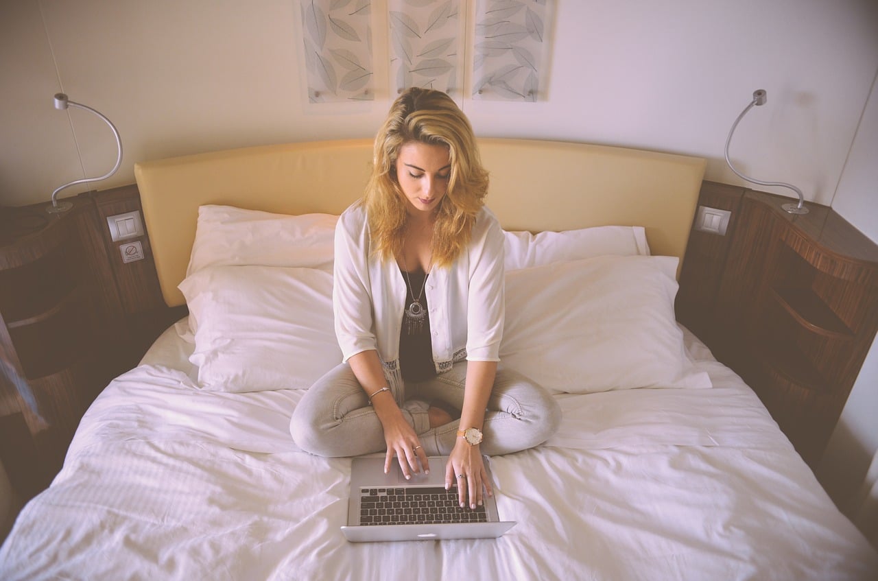 Kobieta z laptopem siedząca na łóżku