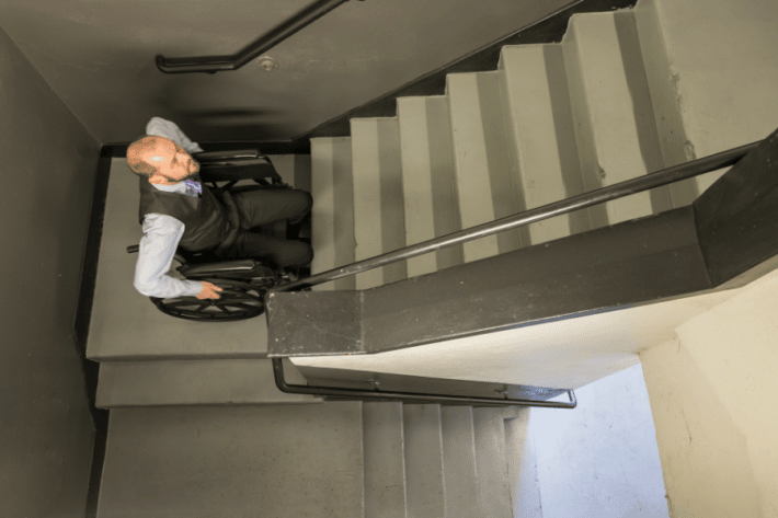 mężczyzna na wóżku inwalidzkim używa schodołazu