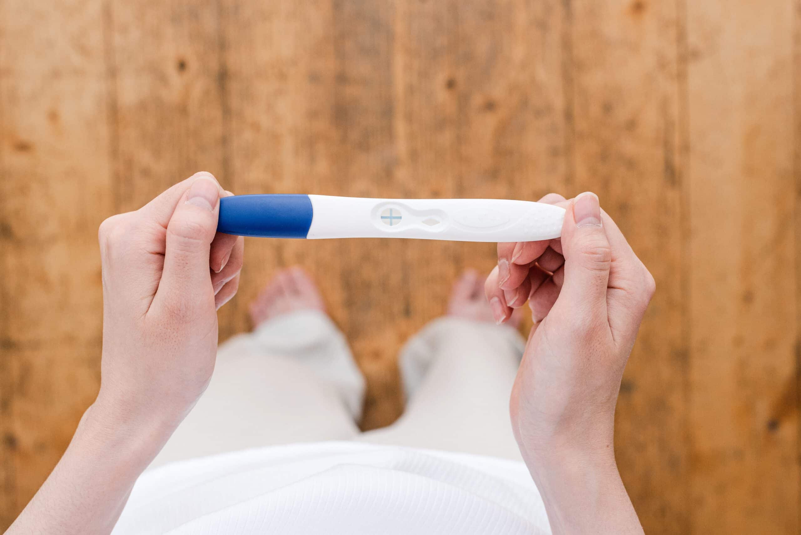 Kobieta z testem ciążowym w pierwszym trymestrze