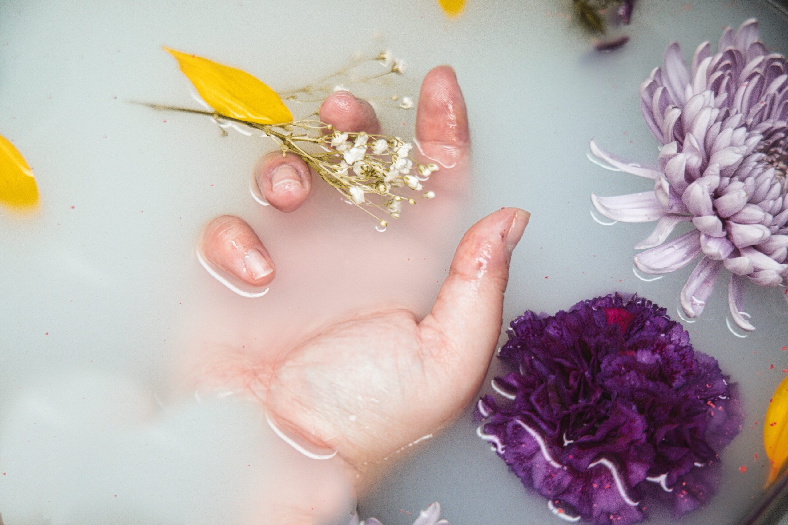 Kobieta z zadbanymi dłoniami bierze kąpiel z kwiatami