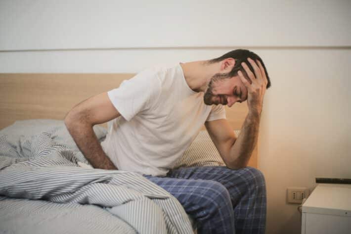 Mężczyzne boli biodro po zewnętrznej stronie i siedzi na łóżu