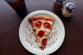 Domowa pizza z pieca leży na białym talerzu na stole