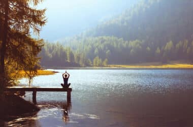 Kobieta uprawia joge na moście koło jeziora