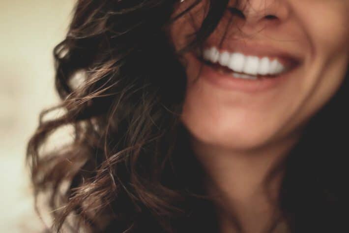 Kobieta z białym uśmiechem urzywa irigatora do zębów