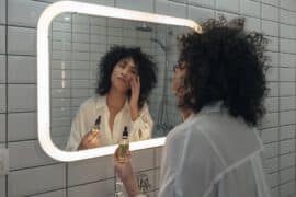 Kobieta w łazience przed ustrem nakłada na twarz olejek