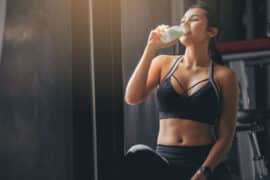 Kobieta na siłowni pije białko dla sportowców