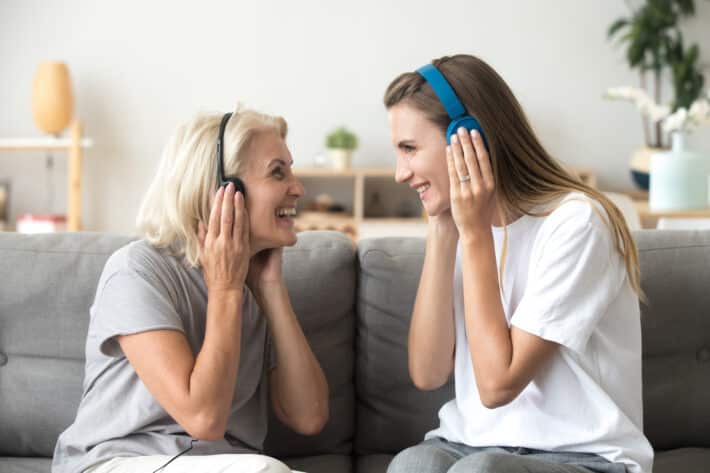 Dwie uśmiechnięte kobiety słuchają muzyki na słuchawkach