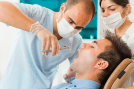 Mężczyzna u stomatolofga na zabiegu ekstrakcji ósemki