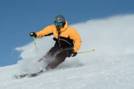 Mężczyzna zjeżdza na nartach mając na sobie kask ochronny
