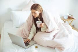 Kobieta leży chora w łóżku i szuka wizytu online