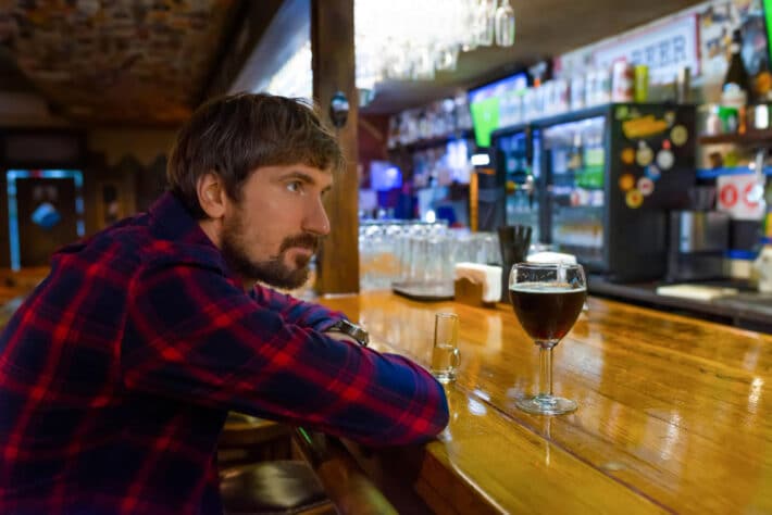 Mężczyzna uzależniony od alkoholu pije wino w barze
