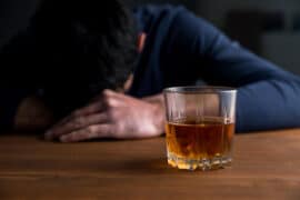 Mężczyzna uzależniony od alkoholu siedzi w barze przy szklance whisky