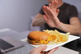 Mężczyzna odmawia zjedzenia hamburgera i frytek, które powodują cholesterol całkowity podwyższony