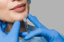 Kobieta wstrzykuje w usta wypełniacz w klinice medycyny estetycznej