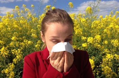 Kobieta z alergię stoi przy polu z rzepakiem