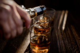 Mężczyzna uzależniony od alkoholu wlewa do kieliszka whisky