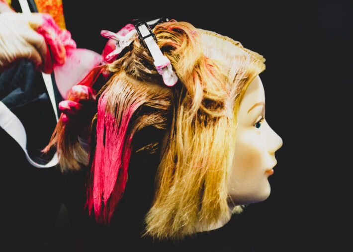 Na tym intrygującym obrazku zobaczysz głowę manekina, na której fryzjerka przeprowadza nietypowe farbowanie od spodu. Ta kreatywna technika koloryzacji zapewnia niezwykły efekt, dodając charakteru i oryginalności do stylizacji włosów.