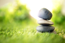 Trzy kamienie na sobie na zielonej trawie, które mają symbolizować technikę relaksacyjną Jacobsona