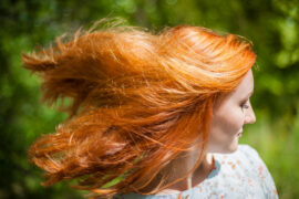 Portrait of a girl with red hair fluttering in the wind.